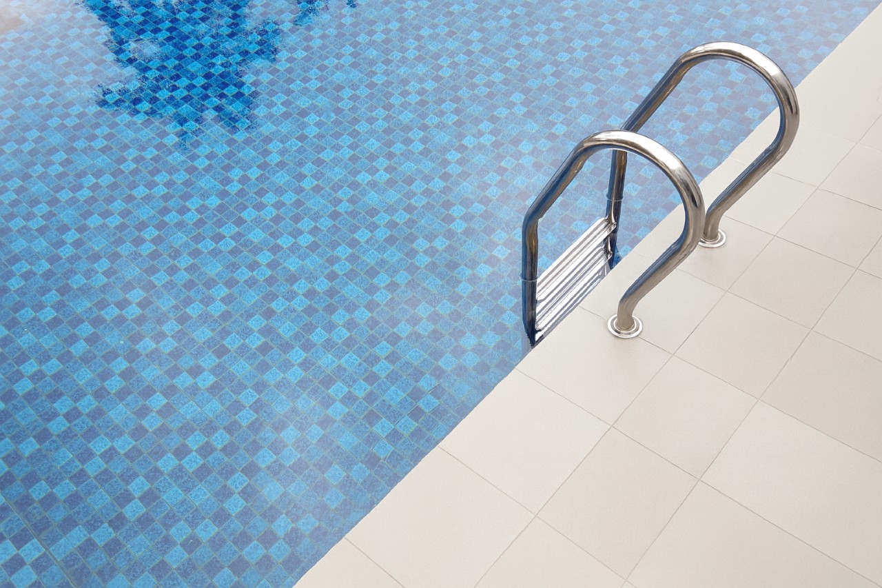 Renovated pool with clean, modern coping and clear blue mosaic tile.